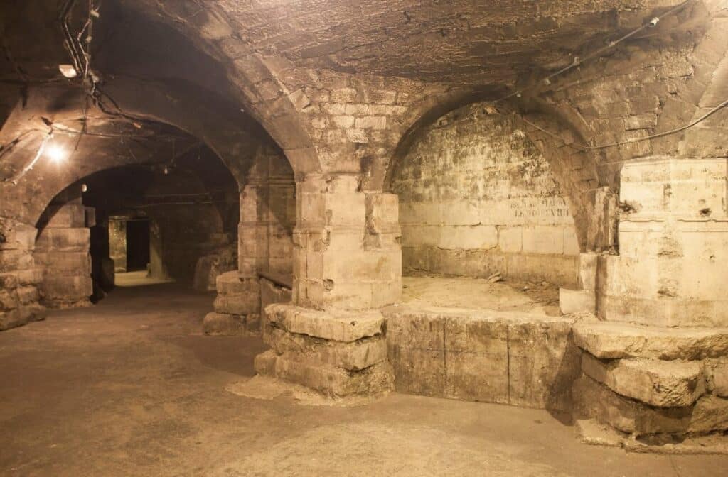Underground crypt ruins beneath Saint-Sulpice Church, with ancient stone arches and worn walls, one of the hidden gems in Paris offering a mysterious glimpse into the city’s forgotten history.