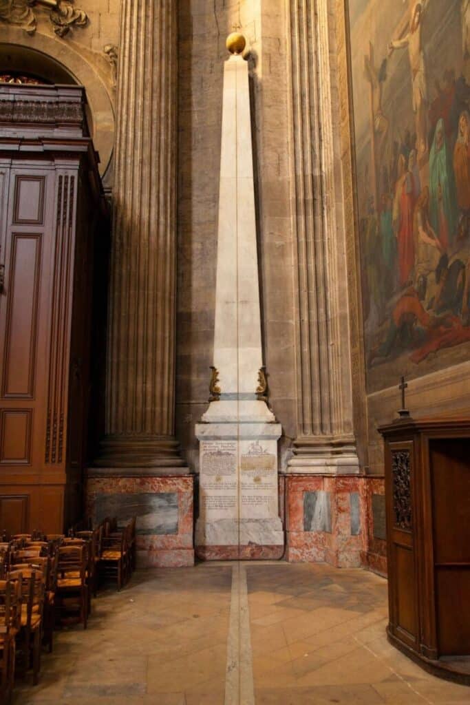 The Paris Meridian gnomon inside Saint-Sulpice Church, an ancient astronomical marker and one of the hidden gems in Paris, featuring a brass line on the floor leading to an obelisk used to track the sun’s position.