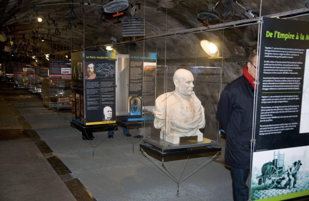 Exhibit inside the Musée des Égouts de Paris (Paris Sewer Museum), featuring historical displays and a bust of Baron Haussmann, one of the hidden gems in Paris where visitors can explore the underground history of the city's sewer system.