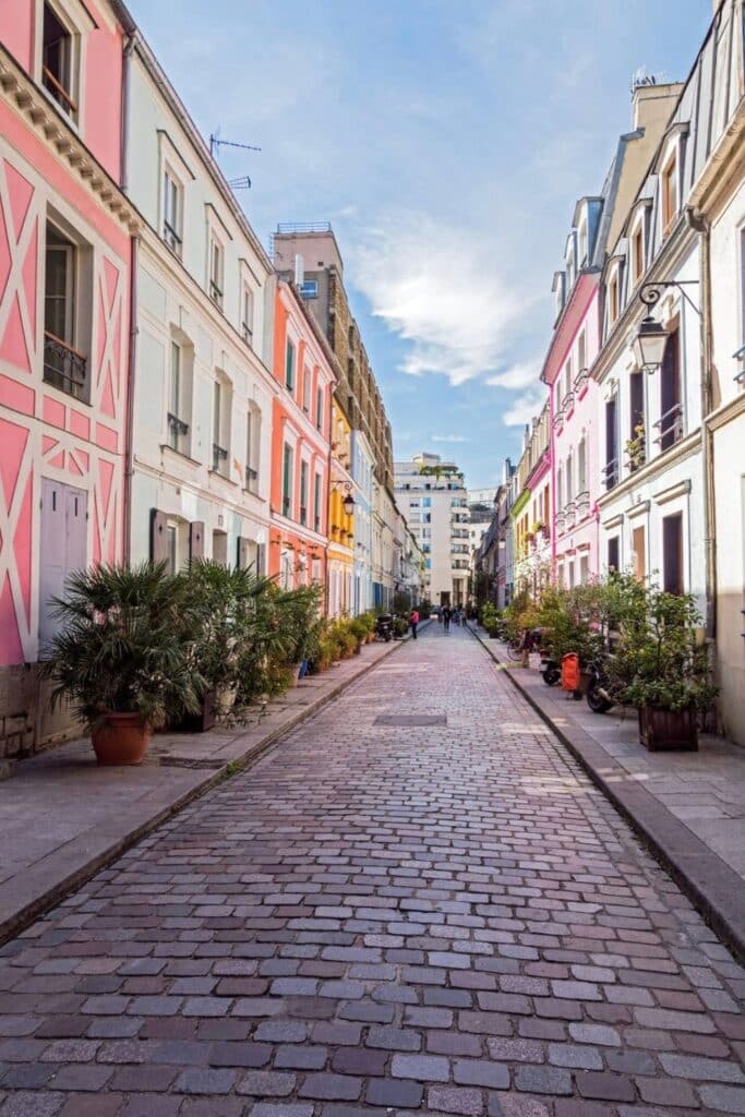 Charming cobblestone street lined with colorful pastel houses on Rue Crémieux, one of the hidden gems in Paris known for its picturesque and Instagram-worthy facades away from the crowds.