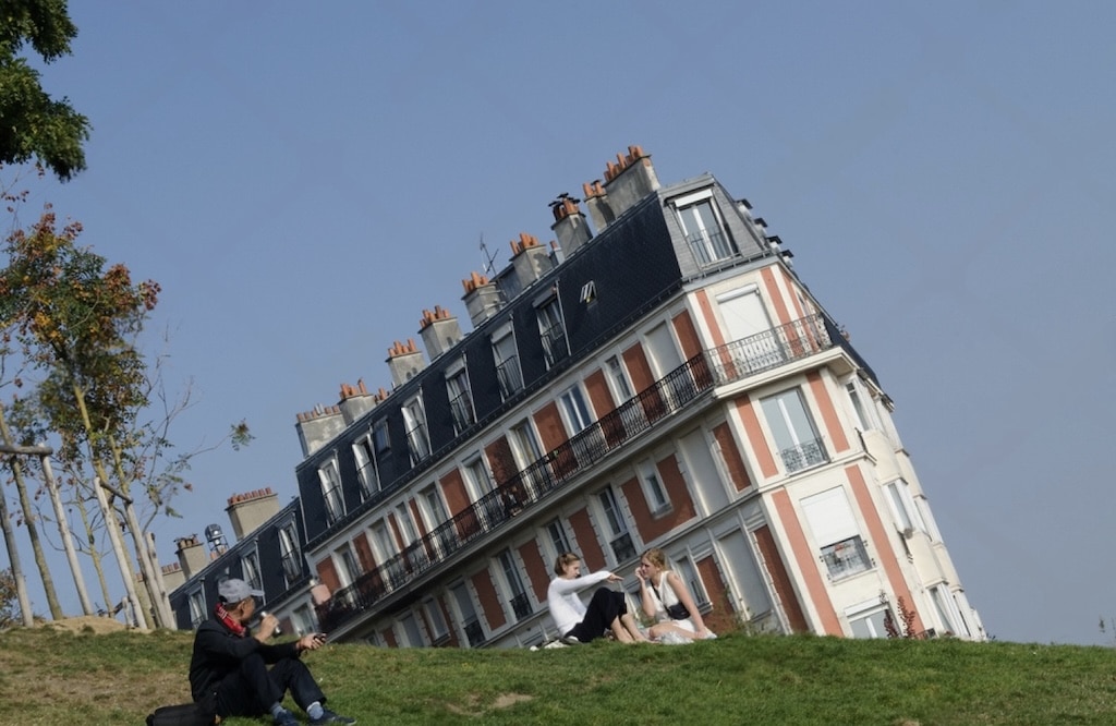 The famous Sinking House of Montmartre in Paris, an optical illusion created by tilting the camera on a grassy hill, one of the hidden gems in Paris for quirky photos and unique views near Sacré-Cœur.