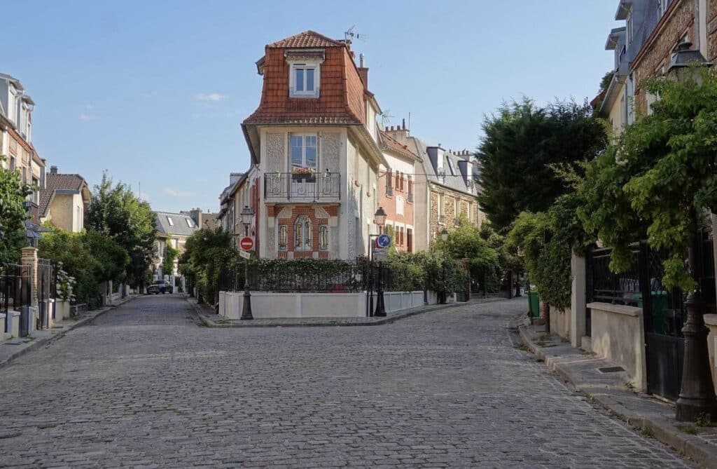 Charming cobblestone street of Villa Léandre in Montmartre, lined with beautiful townhouses and lush greenery, one of the hidden gems in Paris offering a quiet, village-like atmosphere away from the crowds.