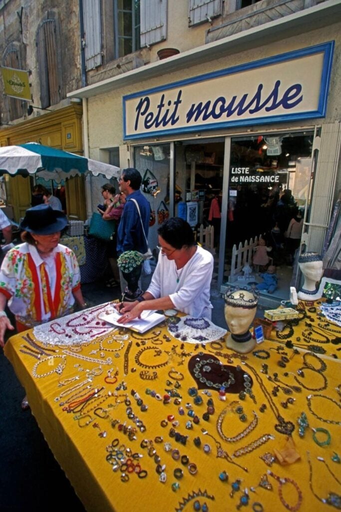 A street vendor selling handmade jewelry and accessories outside "Petit Mousse," offering unique Marseille souvenirs for visitors.