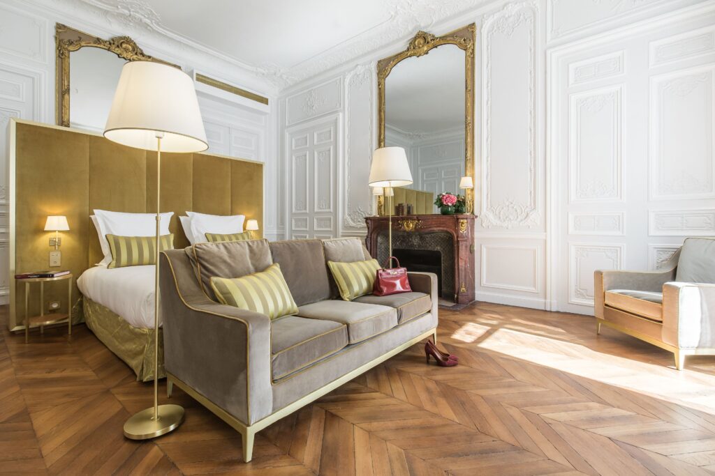 Paris Hotels with Connecting Rooms featuring classic molding, a gold-accented sofa, and hardwood floors.