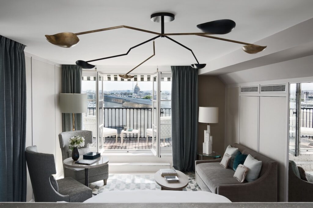 Paris Hotels with Connecting Rooms featuring a balcony view of Paris rooftops and elegant seating.