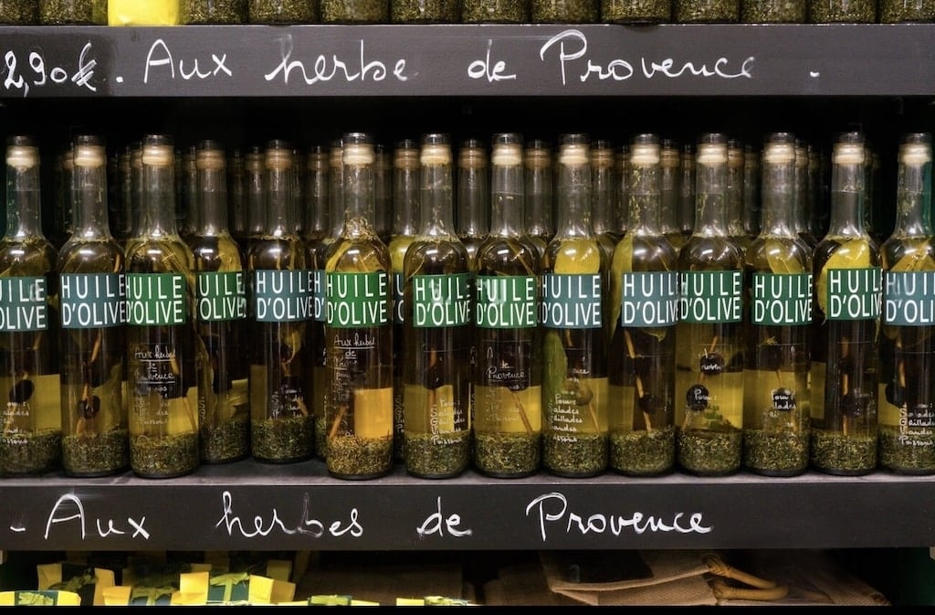 Bottles of olive oil infused with Provençal herbs, a classic culinary delight often chosen as Marseille souvenirs.