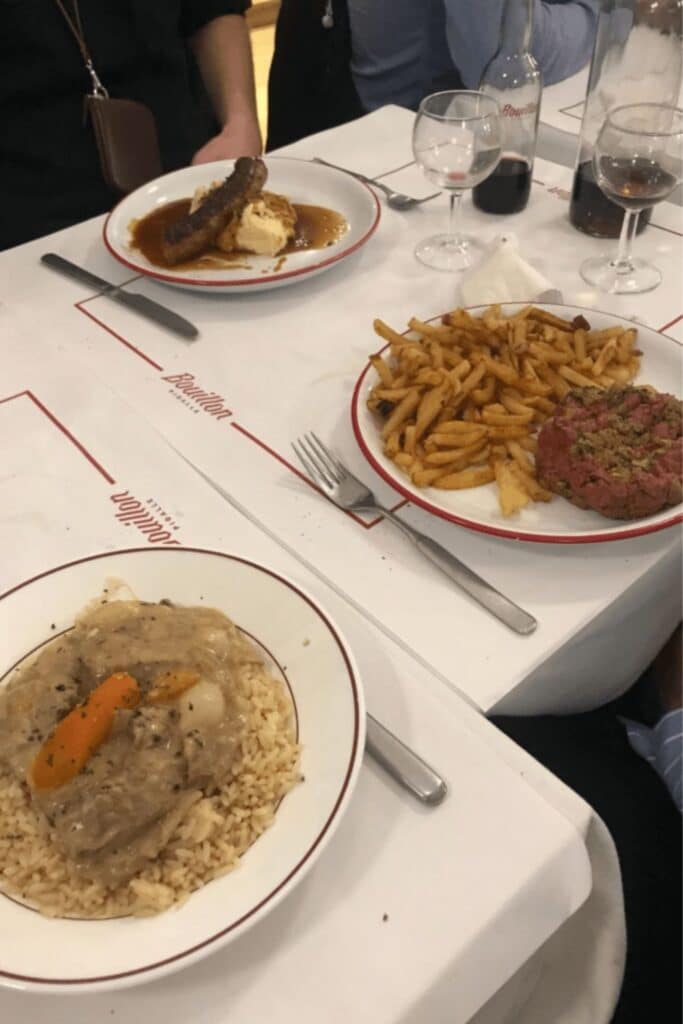 Classic French dishes served at Bouillon Pigalle, one of the must-visit bouillon restaurants in Paris, including steak tartare, sausage with mashed potatoes, and blanquette de veau.