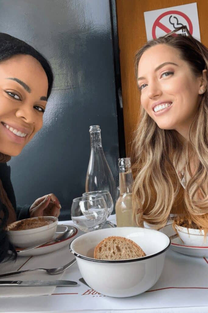 Two friends enjoying lunch at Bouillon Pigalle, one of the most popular bouillon restaurants in Paris, with classic bowls of soup and crusty bread on the table.