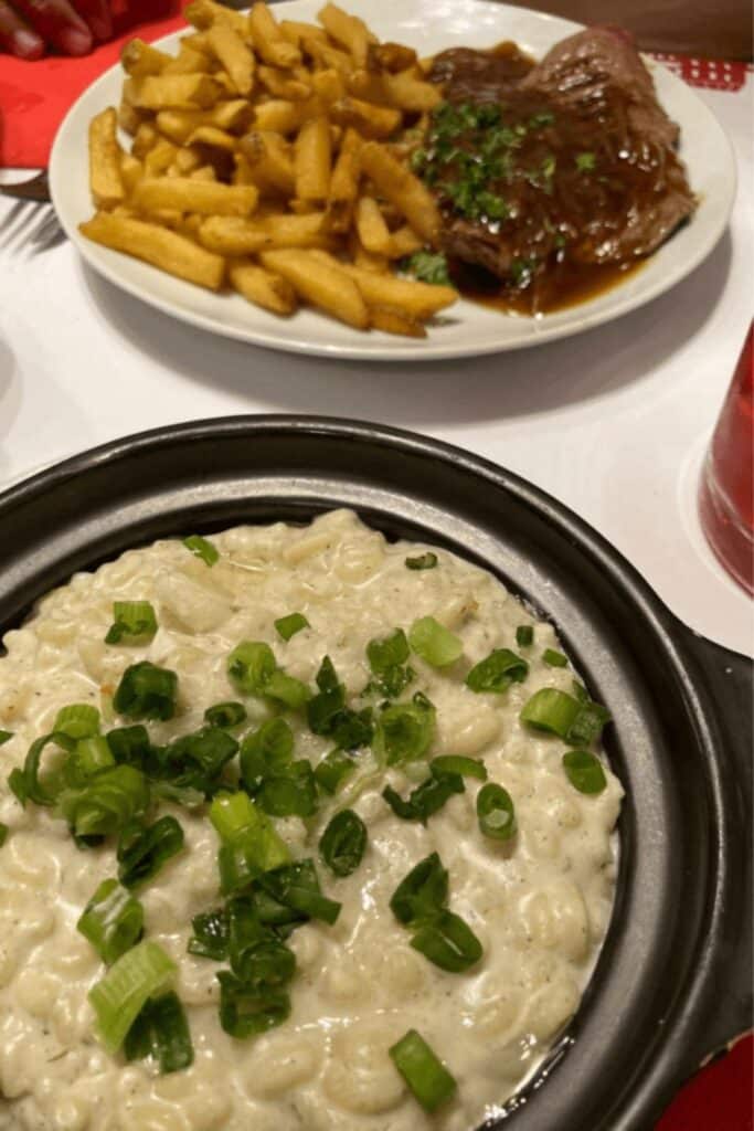 A satisfying meal of steak, fries, and creamy pasta at Le Petit Bouillon Pharamond, showcasing the generous portions bouillon restaurants are known for in Paris.