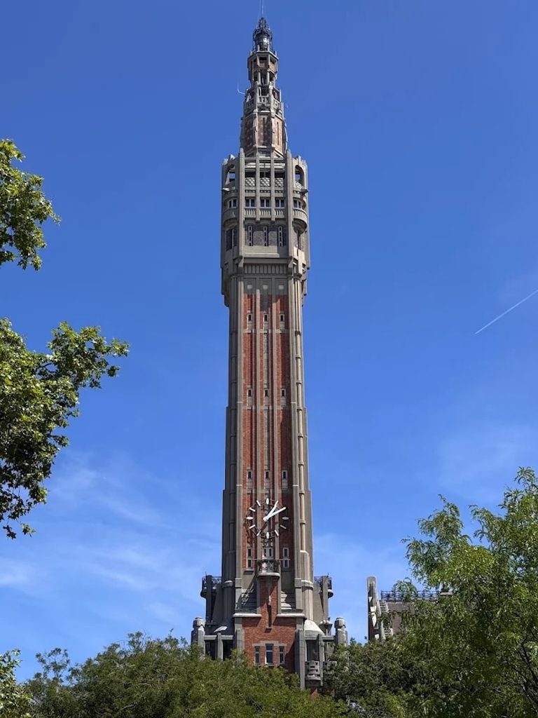 Lille Town Hall Belfry towers above the red-brick Hôtel de Ville under a cloudy blue sky in Lille, France.