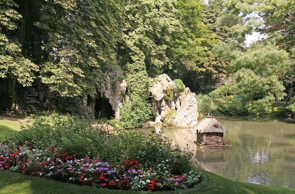 A serene pond surrounded by lush greenery and vibrant flowers in the Jardin Vauban, a peaceful retreat and one of the relaxing things to do in Lille.
