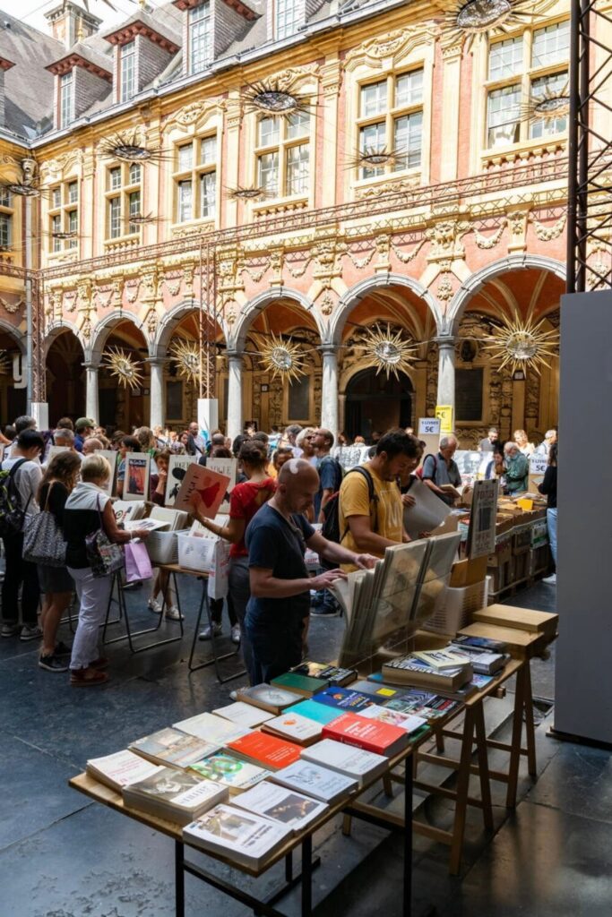 Visitors browse books and art prints at a lively market in the courtyard of the Vieille Bourse, one of the must-see things to do in Lille.