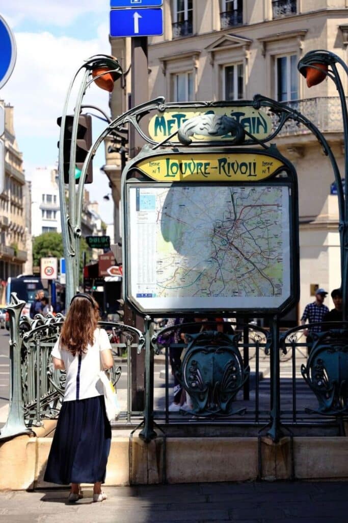 A woman looks at the Louvre-Rivoli Metro map while learning how to use the Metro in Paris and planning her route through the city's system.