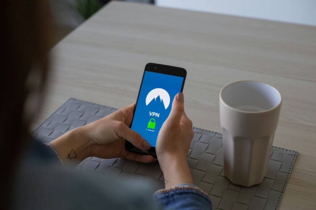 Over-the-shoulder view of a person using a smartphone with a VPN service on the screen, an important digital security tool to include in a 'Packing List for France', ensuring safe internet access while abroad.