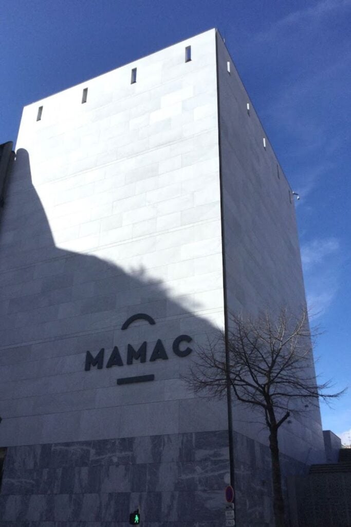 The Modern and Contemporary Art Museum (MAMAC) in Nice, a striking example of modern architecture with its clean lines and minimalist facade, under the Mediterranean sun. A pivotal point of interest for contemporary art lovers in a Nice travel guide, showcasing innovative art in the heart of the city.
