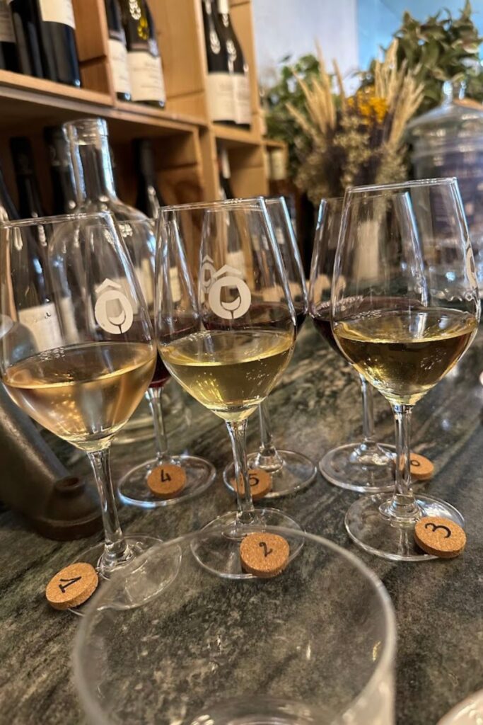 An inviting wine tasting setup at Ô Château, one of the best wine bars in paris, with multiple glasses of white wine sequentially numbered, ready for patrons to savor and compare, set against a backdrop of wine bottles and rustic decor.