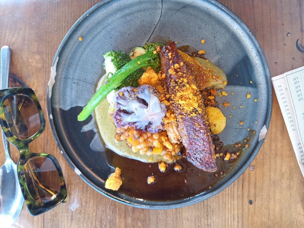 A visually stunning dish from one of the best restaurants in Bordeaux, France, featuring seared duck breast on a bed of creamy lentils, garnished with vibrant green vegetables, purple cauliflower, and sprinkled with crispy bits.