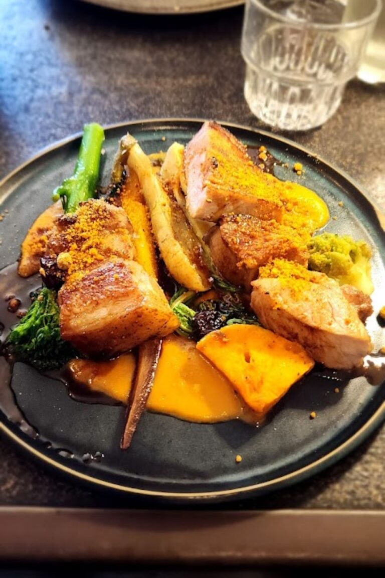 A gourmet dish from one of the best restaurants in Bordeaux, France, featuring succulent pieces of roasted meat, vibrant root vegetables, and a rich sauce, beautifully presented with seasonal greens and garnished with a touch of crunchy topping.