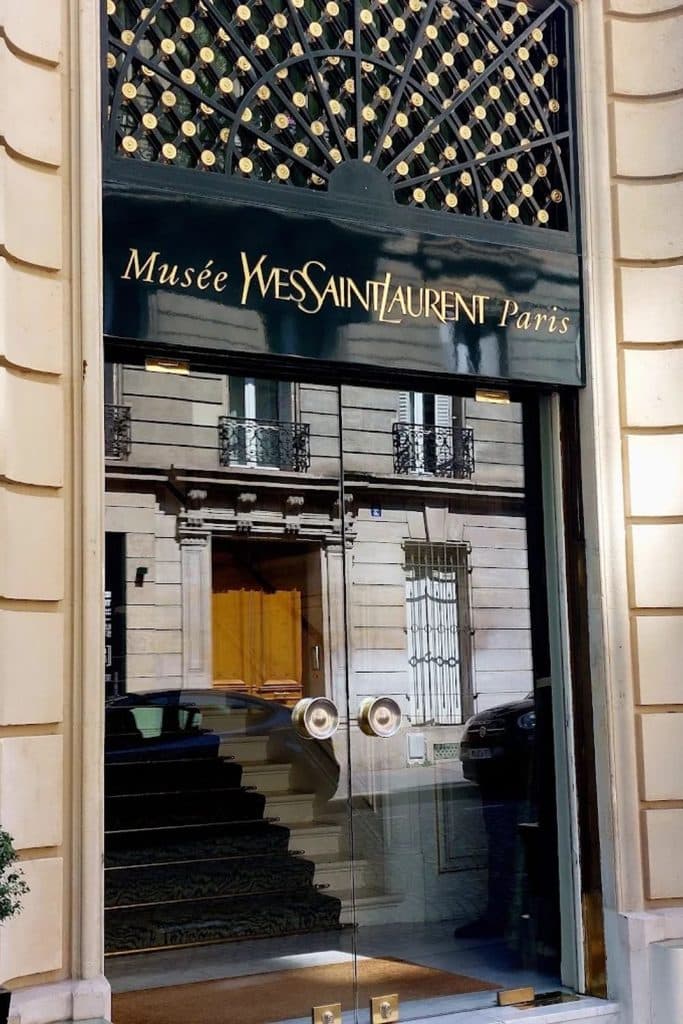 Glass entrance to the Musée Yves Saint Laurent Paris with the museum’s gold lettering above the doors.