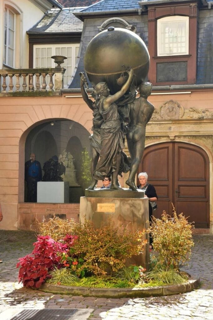 A bronze statue in the courtyard of the Bartholdi Museum in Colmar, France, depicting figures holding up a globe. The museum, dedicated to Frédéric Auguste Bartholdi, the sculptor of the Statue of Liberty, is a must-visit for history and art enthusiasts spending one day in Colmar.