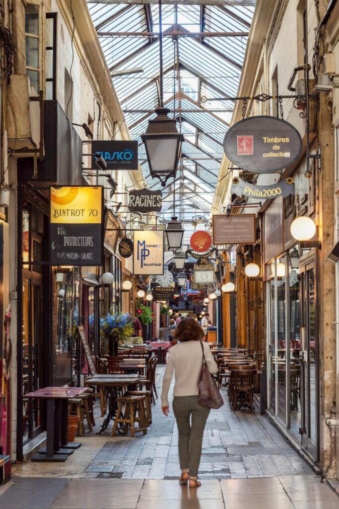 Covered passage in Paris filled with vintage shops, cozy cafés, and hanging signs, one of the hidden gems in Paris that lets visitors explore charming 19th-century arcades away from busy streets.
