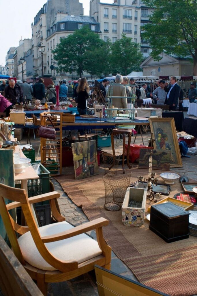 Shoppers browse through antique furniture, paintings, and vintage treasures at Marché d'Aligre, one of the bustling flea markets in Paris.