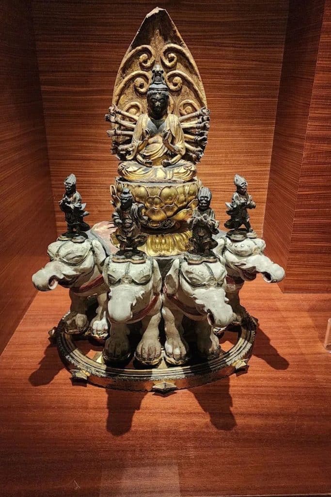 Detailed Buddhist sculpture with seated figures and elephants at the Musée des Arts Asiatiques in Toulon.