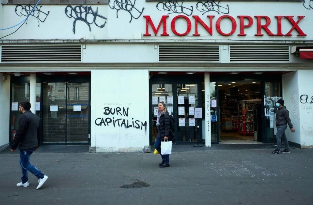 Graffiti reading “Burn Capitalism” on the wall of a Monoprix in Paris, capturing the unrest and visual signs often seen in or near dangerous neighborhoods in Paris, where socioeconomic tensions can be more visible.