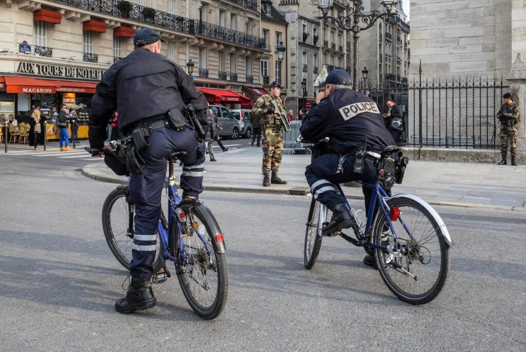 Police officers on bicycles patrolling a central Paris street with heightened security presence, a common scene near dangerous neighborhoods in Paris where vigilance is key for both locals and tourists.