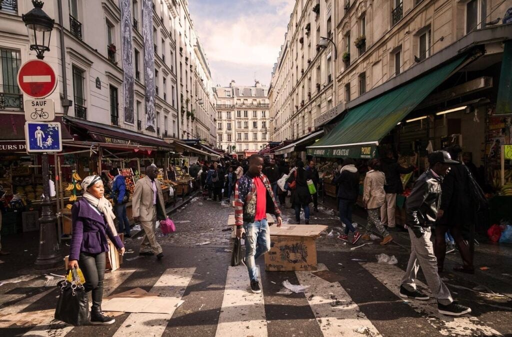 Bustling scene at Rue Dejean street market in La Goutte d'Or, one of the most culturally vibrant yet frequently mentioned dangerous neighborhoods in Paris, where locals shop amid urban grit and energy.