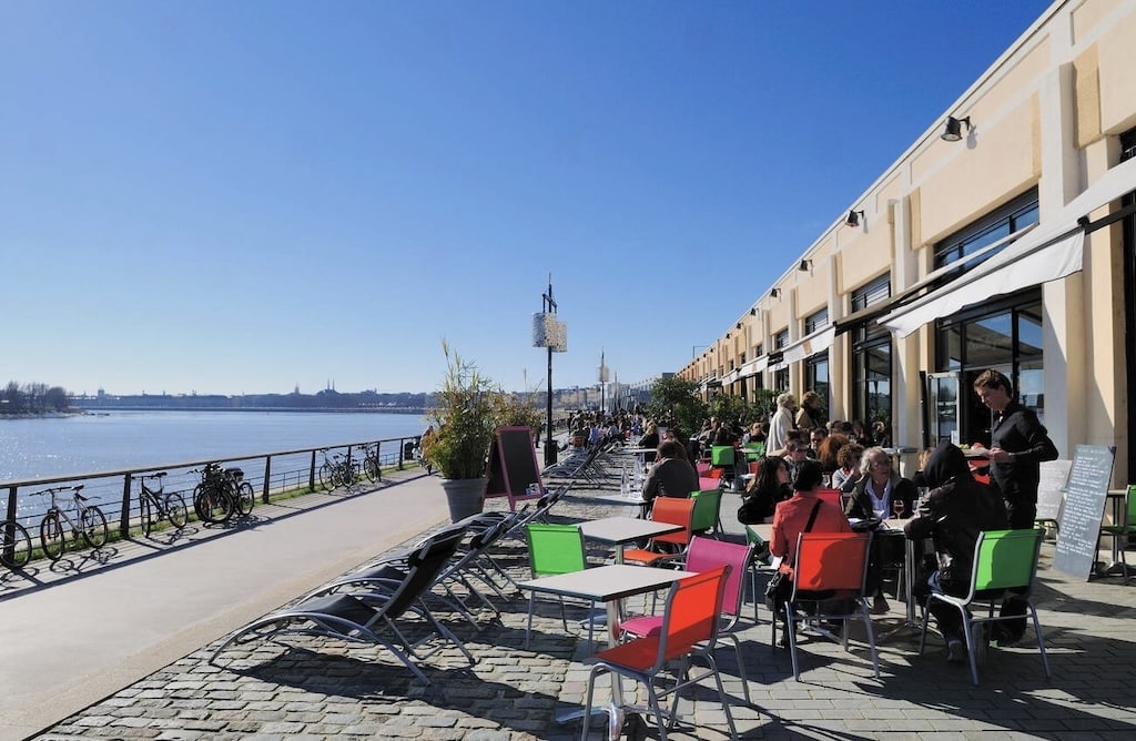 People enjoy dining and relaxing along Bordeaux’s scenic riverfront at Les Quais, a vibrant spot perfect for a leisurely meal or a stroll—one of the top things to do in Bordeaux.