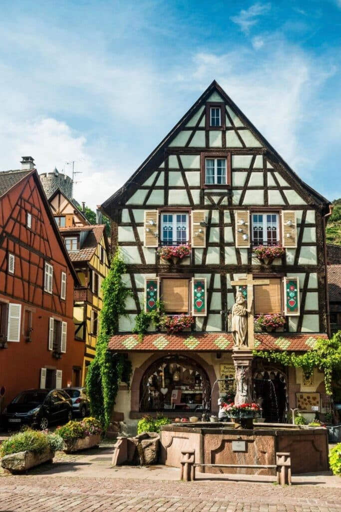 Charming fairytale houses and a beautiful fountain in Eguisheim, one of the most picturesque places to visit in Alsace, with colorful half-timbered buildings and a peaceful village square.