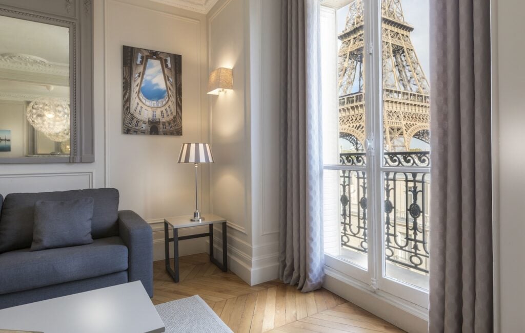A sophisticated hotel suite featuring elegant decor and a balcony with a striking close-up view of the Eiffel Tower, ideal for Paris hotels with Eiffel Tower views.