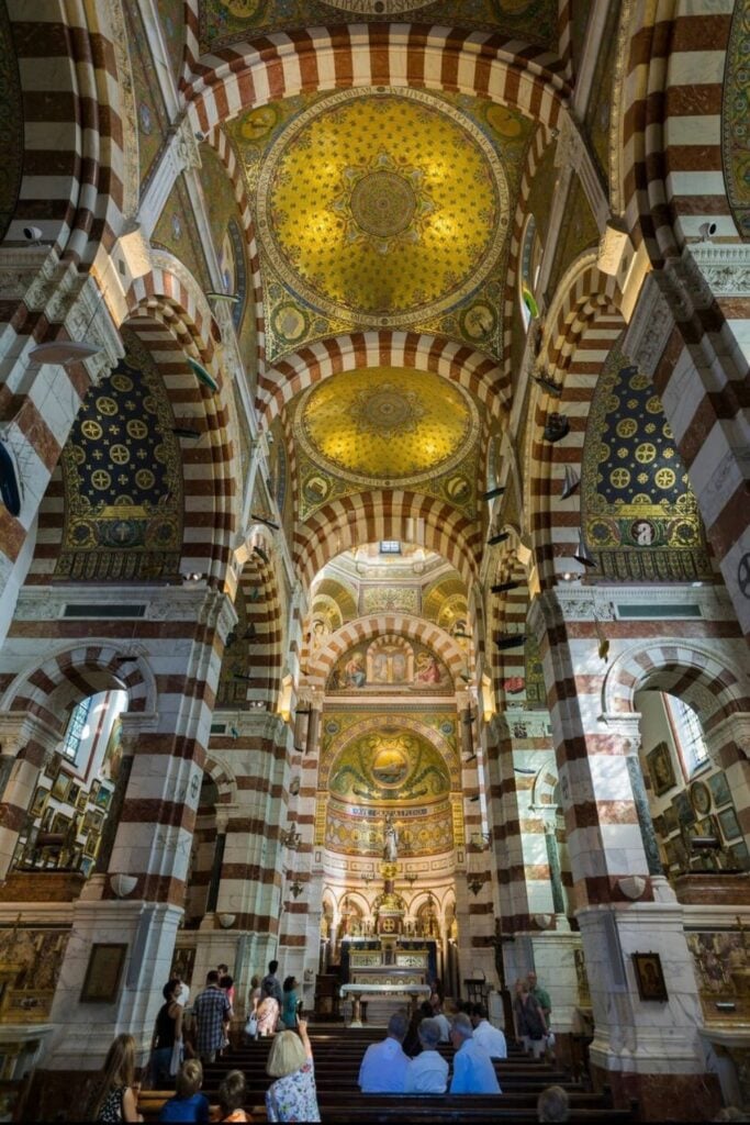 The ornate interior of Notre-Dame de la Garde, with its golden mosaics and intricate striped arches, is a breathtaking sight and one of the top things to do in Marseille France.