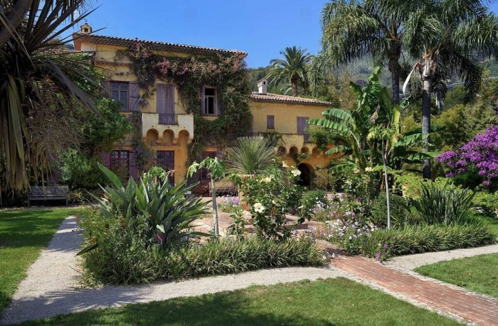 A charming villa with Mediterranean architecture is surrounded by lush tropical gardens, making it a must-see for those exploring the best things to do in Menton France.