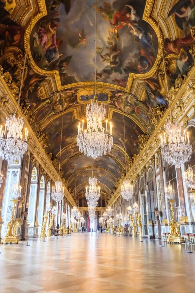 The opulent Hall of Mirrors in the Palace of Versailles, adorned with gilded details and sparkling chandeliers, is a must-see highlight for day trips from Paris France.