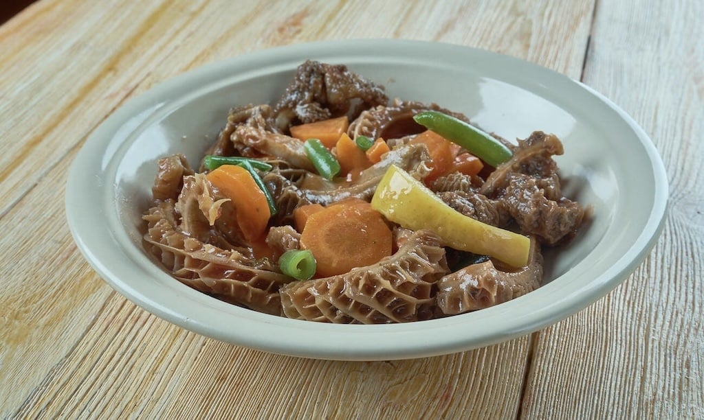 A bowl of hearty tripes à la mode de Caen, a slow-cooked tripe stew with vegetables, representing the rich flavors of traditional French foods.