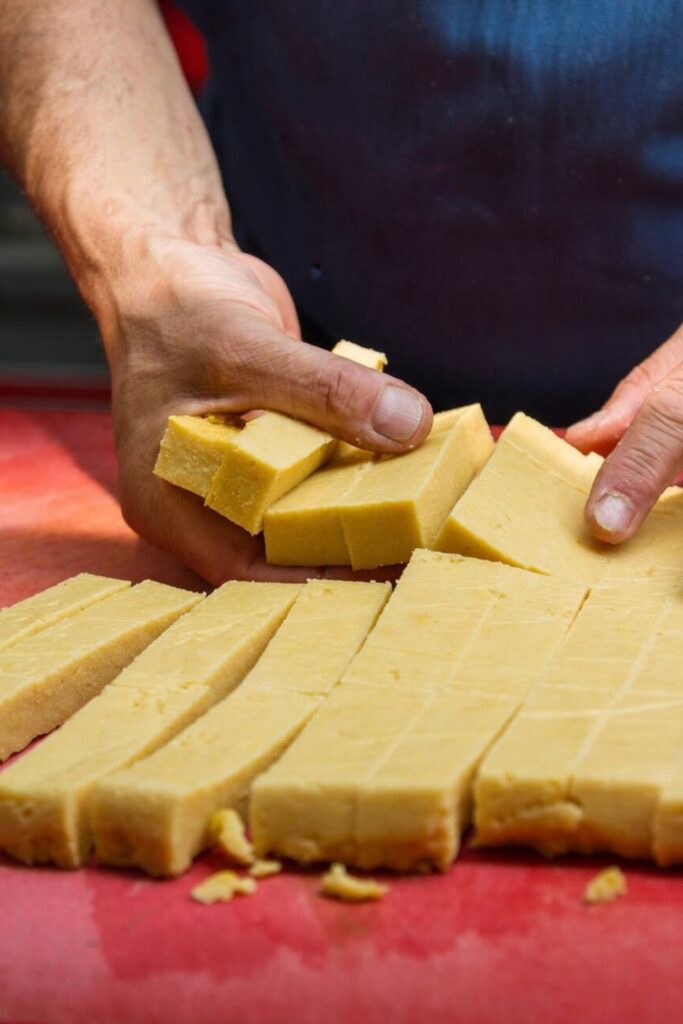A close-up of a chef cutting freshly made panisse, a crispy chickpea flour delicacy, a must-try in any Marseille Food Guide.