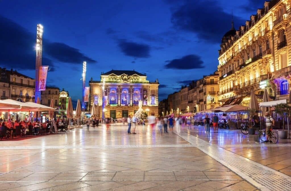 Experiencing the vibrant atmosphere of Place de la Comédie at night, with its illuminated architecture, bustling cafés, and lively ambiance, is one of the must-do things to do in Montpellier.
