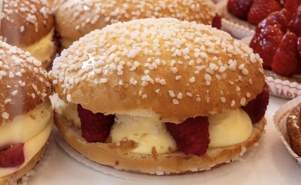 A decadent Tarte Tropézienne filled with rich cream and fresh raspberries, topped with pearl sugar—a sweet highlight in any Marseille Food Guide.