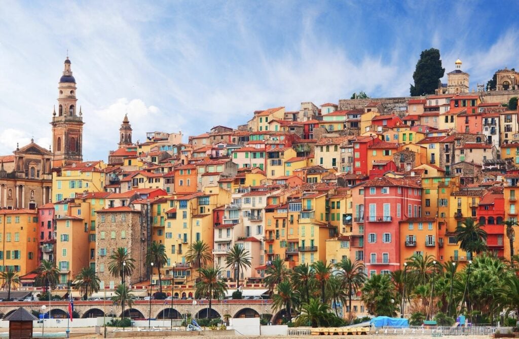 A vibrant hillside of pastel-colored buildings, palm trees, and historic architecture makes exploring the Old Town one of the most picturesque things to do in Menton France.
