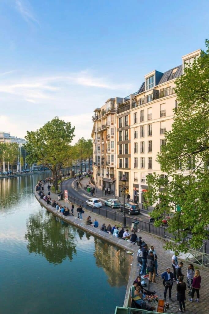 Locals and travelers enjoying a sunny afternoon along Canal Saint-Martin in the 10th arrondissement—one of the best budget-friendly areas when deciding where to stay in Paris.