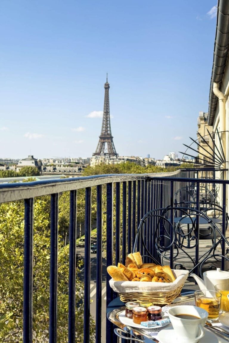 Balcony breakfast with fresh pastries and coffee overlooking the Eiffel Tower and Parisian trees, perfect for cheap hotels with Eiffel Tower view.